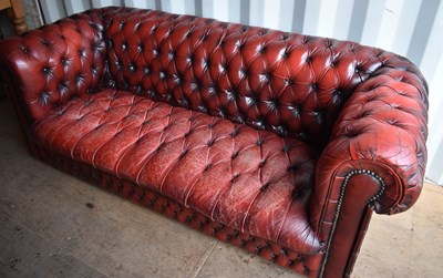 Lot 515 - A two seater red leather Chesterfield settee...