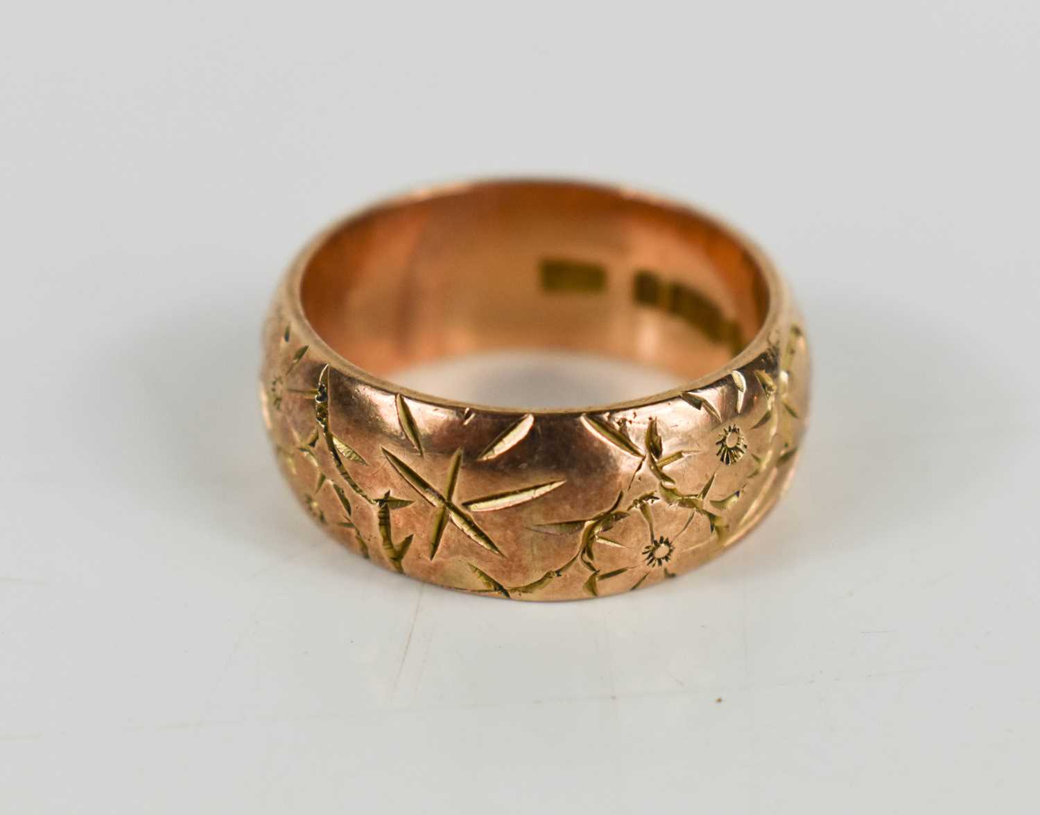 Lot 88 - A 9ct rose gold band, engraved with flowers,...