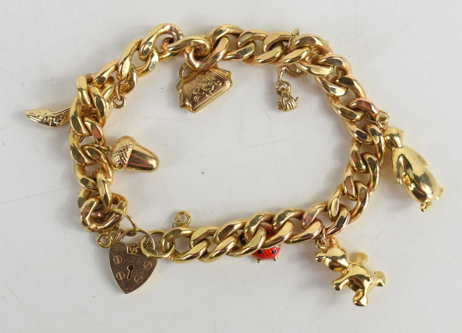 Lot 41 - A 9ct gold curb link charm bracelet with heart...