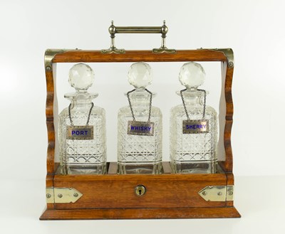 Lot 129 - An oak cased antique tantalus containing three...