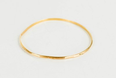 Lot 204 - An 18ct gold bangle with engraved detail,...