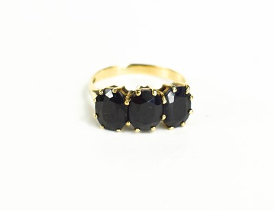 Lot 85 - A 9ct gold and dark sapphire three stone ring,...