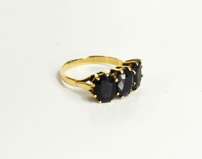 Lot 9 - A 9ct gold and dark sapphire three stone ring,...