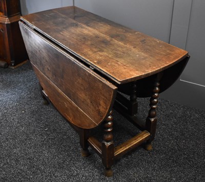 Lot 555 - A 18th century oak drop leaf table with turned...