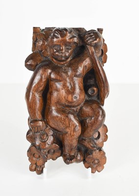 Lot 452 - A carved oak cherub amongst flowers, 17 by 9cm.