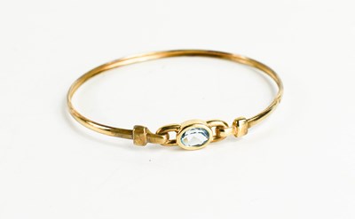 Lot 106 - A 9ct gold and aquamarine bangle the oval cut...