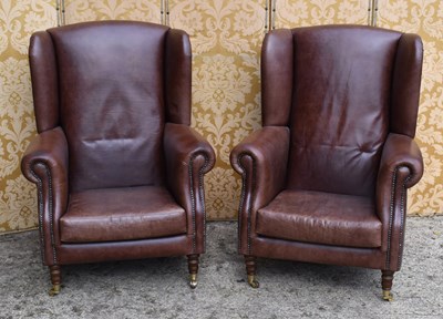 Lot 558 - A pair of brown leather wingback armchairs...