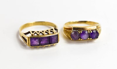 Lot 111 - Two amethyst three stone rings, one set with...