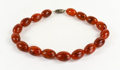 Lot 140 - A red amber beaded necklace, the oval beads...