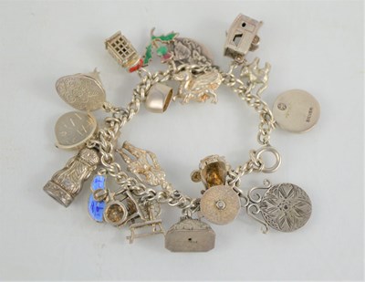 Lot 228 - A silver charm bracelet with twenty charms,...