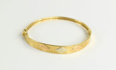 Lot 161a - An 18ct gold bangle with three raised diamond...