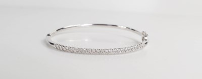 Lot 94 - A 10ct white gold and diamond bangle, the...