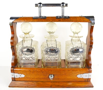 Lot 180 - An early 20th century oak tantalus, with three...