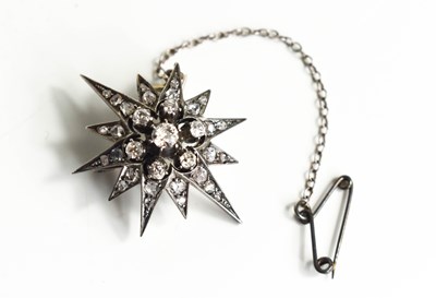 Lot 16 - A white metal and diamond starburst brooch,...