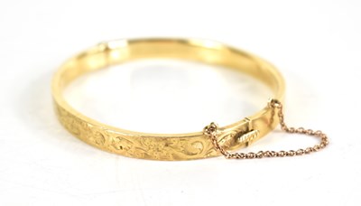 Lot 120 - A 9ct gold bangle, engraved with foliate...