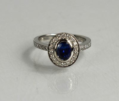 Lot 93 - An 18ct white gold, sapphire and diamond halo...