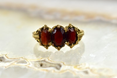 Lot 115 - A 9ct gold and garnet three stone ring, size P,...