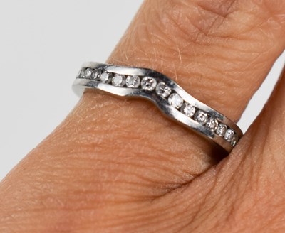 Lot 17 - A platinum and diamond wedding band, shaped to...