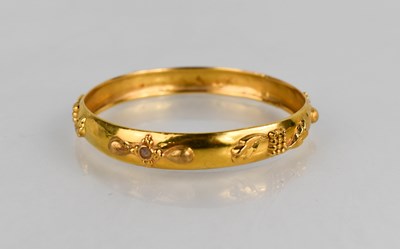 Lot 441 - A 21ct gold bangle, with leaf and quatrafoil...