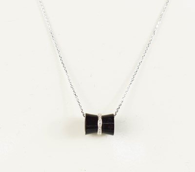 Lot 411 - An 18ct white gold onyx and diamond pendant...