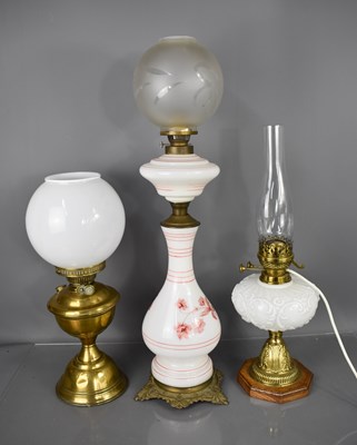 Lot 60 - Three paraffin lamps, one in brass with glass...