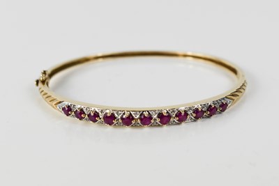 Lot 116 - A 9ct gold, ruby and diamond bangle, with...
