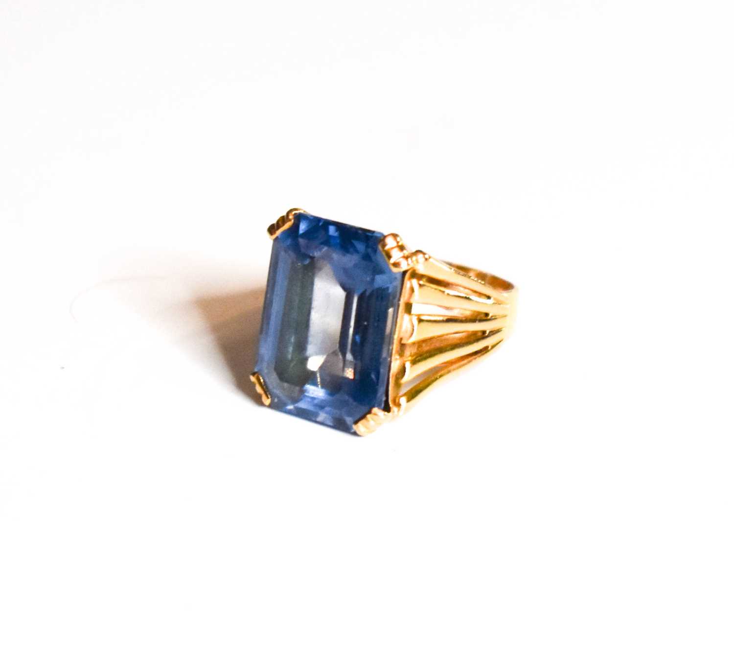 Lot 10 - A gold dress ring set with emerald cut blue...