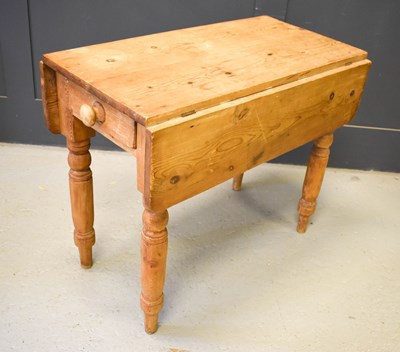 Lot 388 - An antique pine drop leaf kitchen table with a...