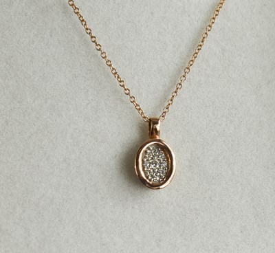 Lot 107 - A 9ct rose gold and diamond set oval pendant...