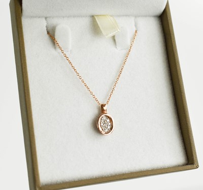 Lot 107 - A 9ct rose gold and diamond set oval pendant...
