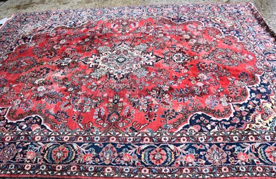 Lot 539 - A large wool rug of Persian design, the red...