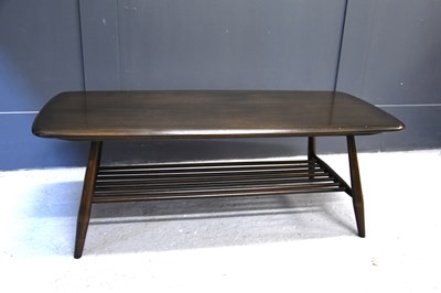 Lot 563 - An Ercol dark elm coffee table with magazine...